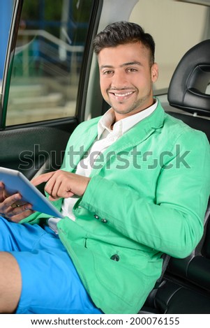 Portrait of young Indian business man sitting in the back seat of your car.