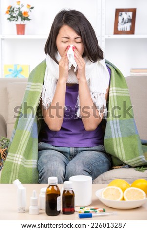 Young asian woman treats colds. Medicines and lemons on the table.