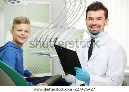 Patient at dentist office. Dentist and little patient are looking at camera and smiling.