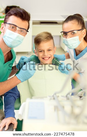Portrait of friendly doctor, nurse and little patient at dentist\'s office. They are looking at the camera.