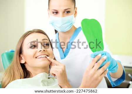 Happy female patient with doctor are looking at mirror in clinic.