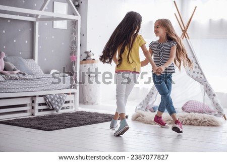 Two happy little sisters sitting in a meadow