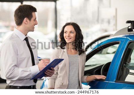 Attractive woman at car salon with consultant choosing a car.