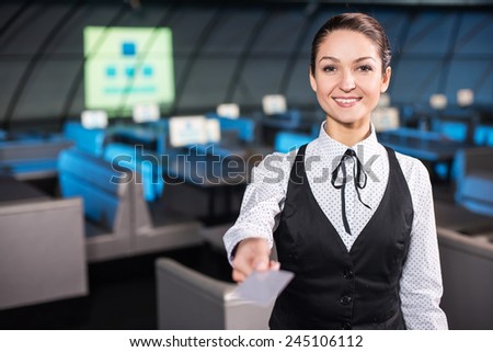Young smiling business woman is holding a discount card. Modern conference hall in background.