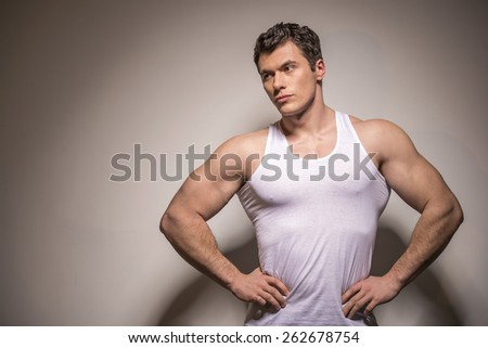 Attractive young man is standing is holding hands on your waist. Isolated on light background.