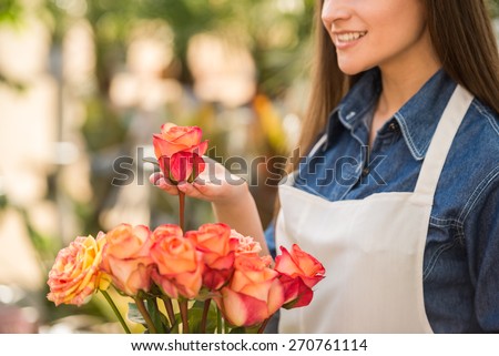 Close-up. Young female florist holding a rose in flower shop.