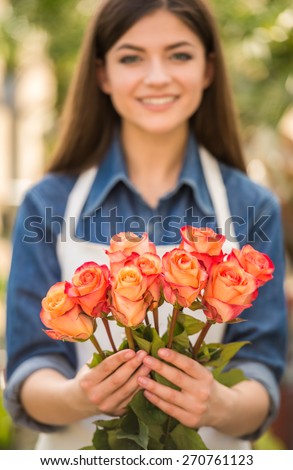Close-up. Female florist holding bouquet with roses. Focus on roses.