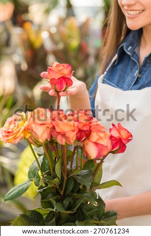 Young female florist holding a rose in flower shop.