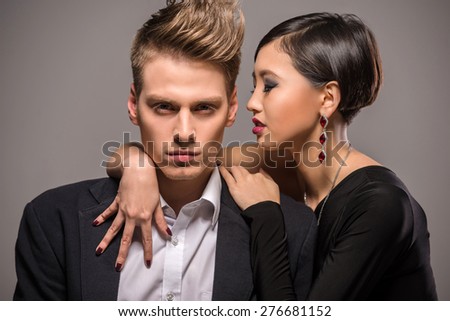 Young fashionable couple dressed in formal clothing posing in the studio on dark background. Fashion portrait. Passion.