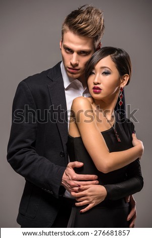 Young fashionable couple dressed in formal clothing posing in the studio on dark background. Fashion portrait. Passion.