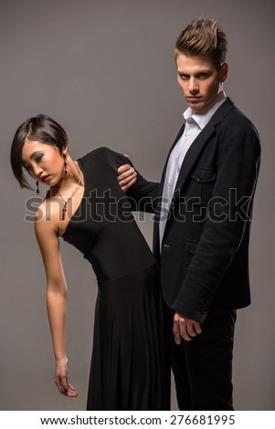 Young fashionable couple dressed in formal clothing posing in the studio on dark background. Fashion portrait. Jealousy.