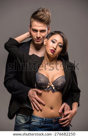 Young fashionable couple in tuxedos posing in the studio on dark background. Fashion portrait. Passion.