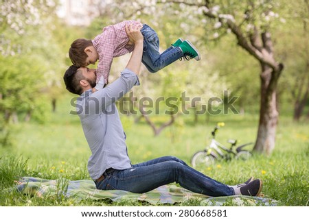 Happy family having fun outdoors in spring garden. Father playing with child. Family concept.