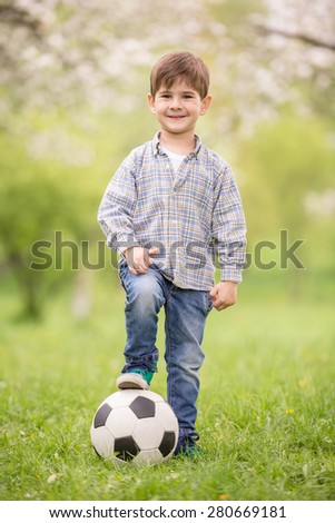 Little cute boy dressed casual playing with soccer ball in summer park.