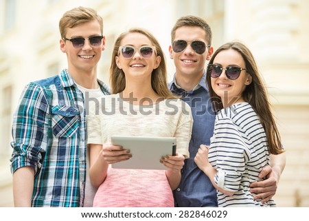 Double couple date. Friends walking down the street together and using digital tablet.