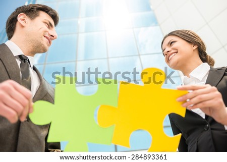 Image of business people wanting to put two pieces of puzzle together.