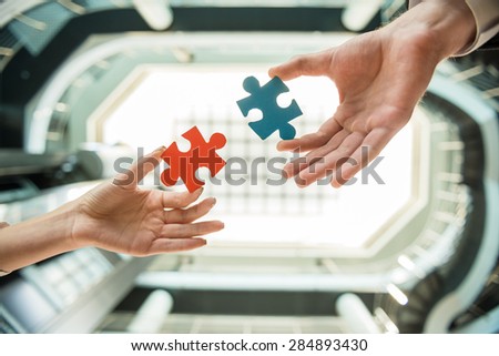 Close-up of business people wanting to put two pieces of puzzle together.