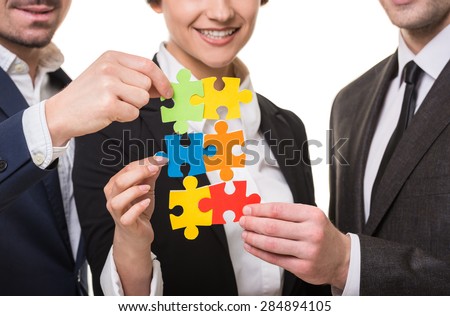 Close-up of business people wanting to put pieces of puzzle together.