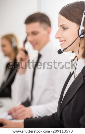 Attractive positive young colleagues working in call center office. Side view.