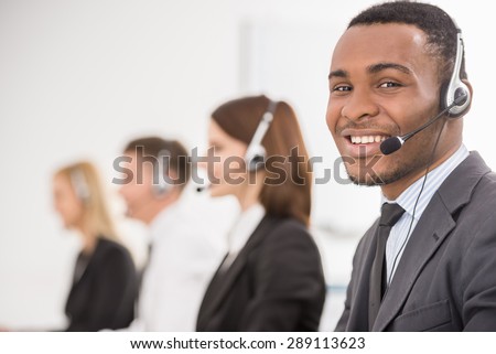 Group of agents sitting in line in a bright call centre.