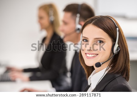 Smiling beautiful lady working at call center with colleagues in office.