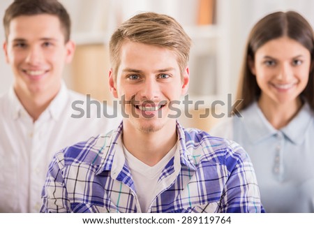 Group of young colleagues dressed casual standing together in modern office and smiling to camera.