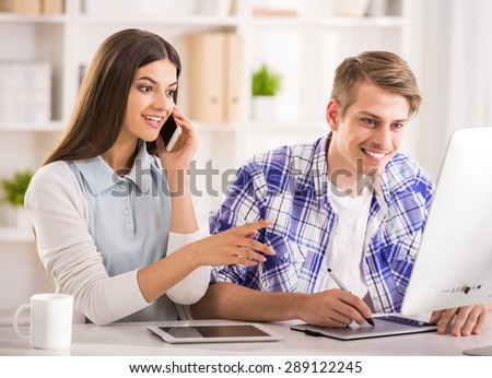 Young attractive couple sitting at the table and using computer.
