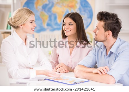 Beautiful woman sitting at office with clients and proposing hot tours to them.