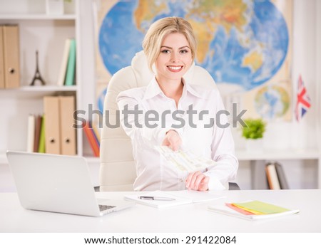 Female travel agent sitting at office and holding tickets.