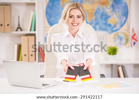 Female travel agent sitting at office and holding tickets. Close-up.