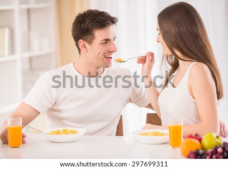 Cute couple having breakfast together. Woman feeding her boyfriend with corn flakes.