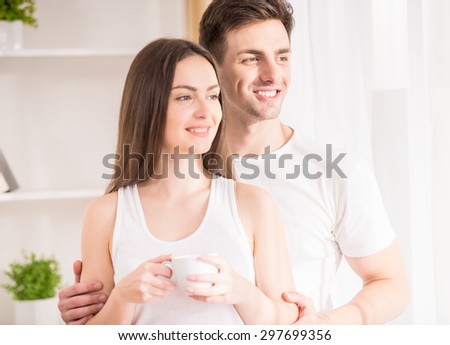 Image of cheerful couple looking at the window and dreaming about beautiful life.