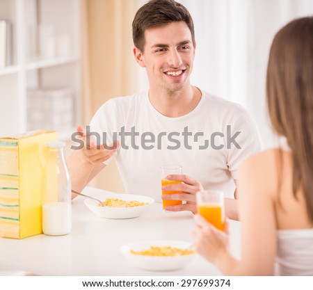 Cute couple sitting at the table in the kitchen and having breakfast together.