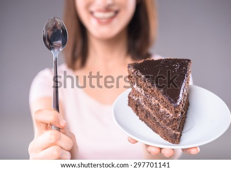 Sweet temptation. Young woman holding plate with chocolate cake and dessert spoon.