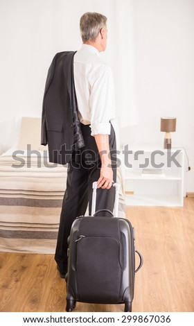 Businessman with his suitcase at the hotel room. Back view.