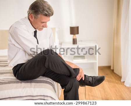 Mature man dressed formal going to bed after hard working day at the hotel room.