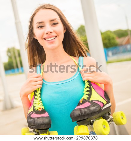 Happy woman holding her roller skates by the laces on neck.