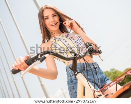 Flirty beauty. Young brown hair woman with bicycle looking at camera and smiling.