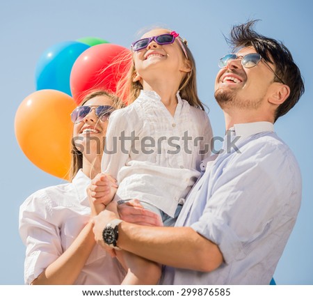Happy family with balloons looking up outdoor on a summer day.