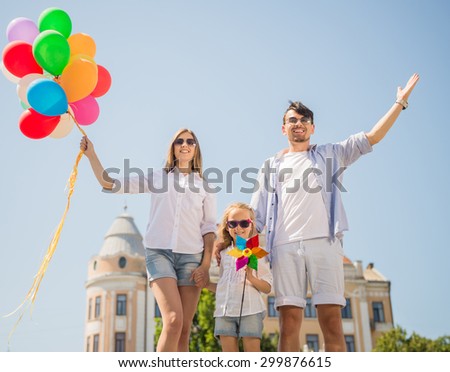 Happy family holding colorful balloons outdoor. Mom, dad and little daughter playing together.