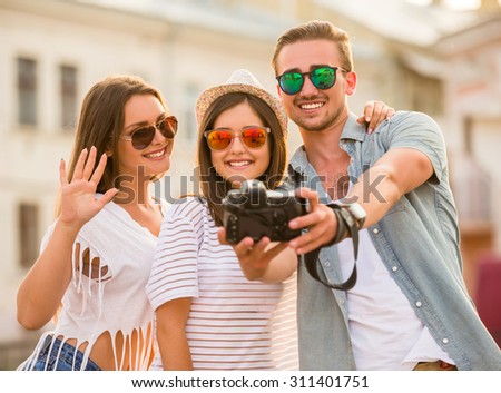 Friendship, leisure and people concept. Young people are taking selfie photo with photo camera, outdoors, in the town.