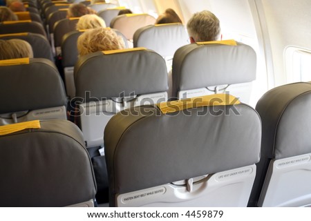Aircraft interior with passenger people, focus at the front seat