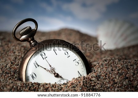 Old pocket watch buried in sand