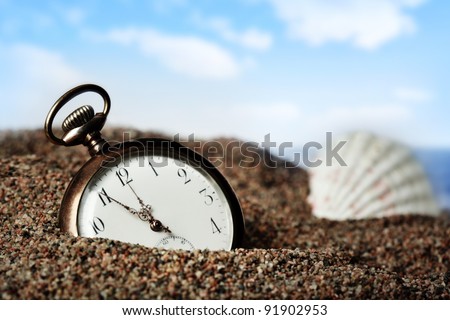Old pocket watch buried in sand