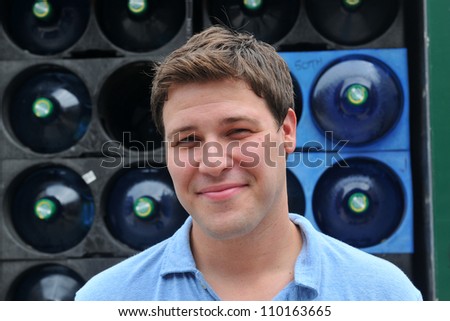 handsome man in blue shirt smiling in front of water delivery track