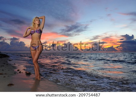 Model posing in bikini at early morning sunrise over the ocean at tropical location