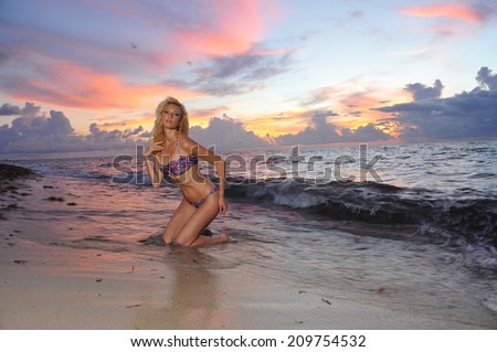 Model posing in bikini at early morning sunrise over the ocean at tropical location