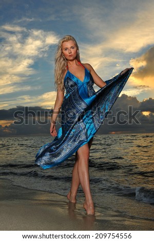 Model posing in beach dress at early morning sunrise over the ocean at tropical location