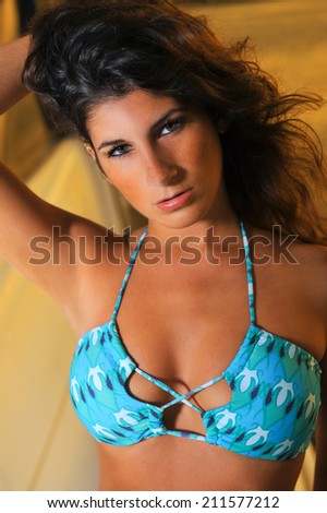 Fashion portrait of young sexy brunette girl in bikini posing on the boat.