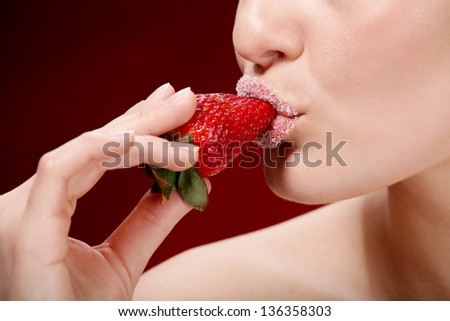 Young woman\'s mouth with red strawberry covered with sugar